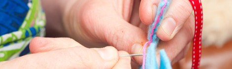 hands working a blanket stitch on the edge of two pieces of fabric