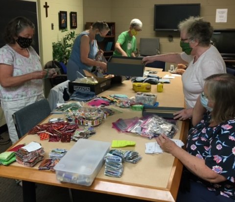 5 women around tables of supplies