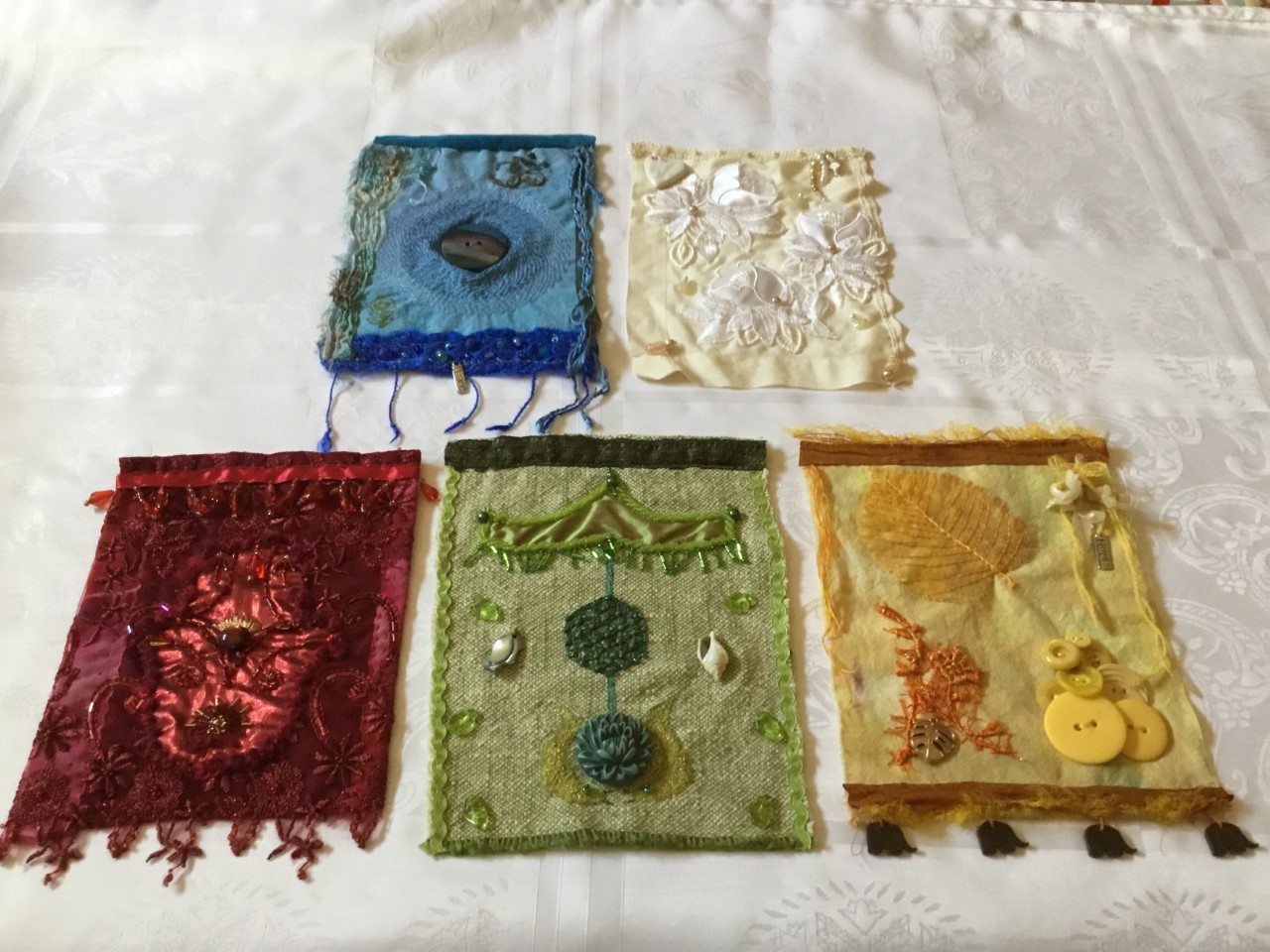 5 flags in different colourways with embroidery and found objects