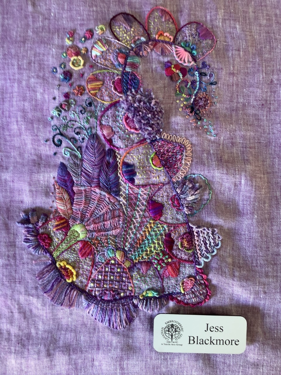 purple toned flag with dense, abstract embroidery