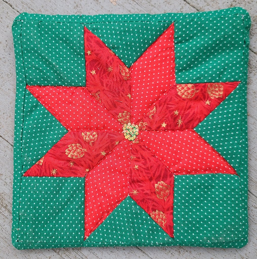 quilted 8-point star in red on green background, as a mug rug
