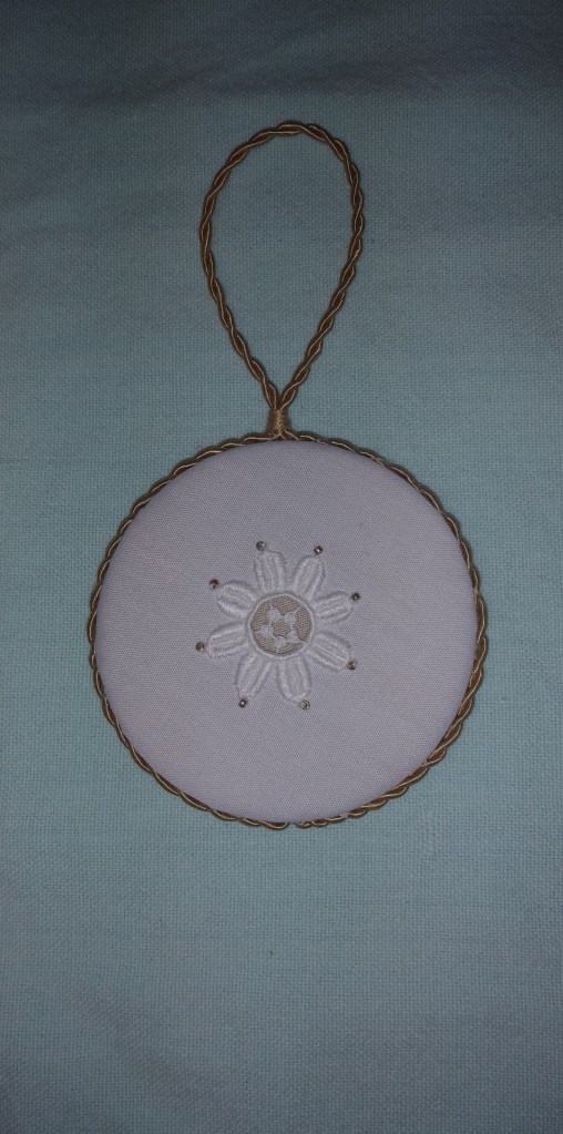 small whitework ornament with gold cord
