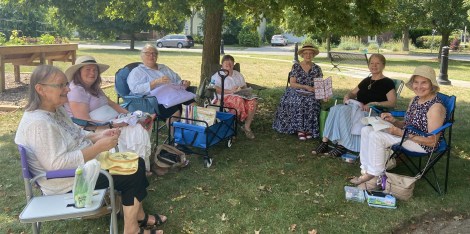 7 women in a circle stitching together