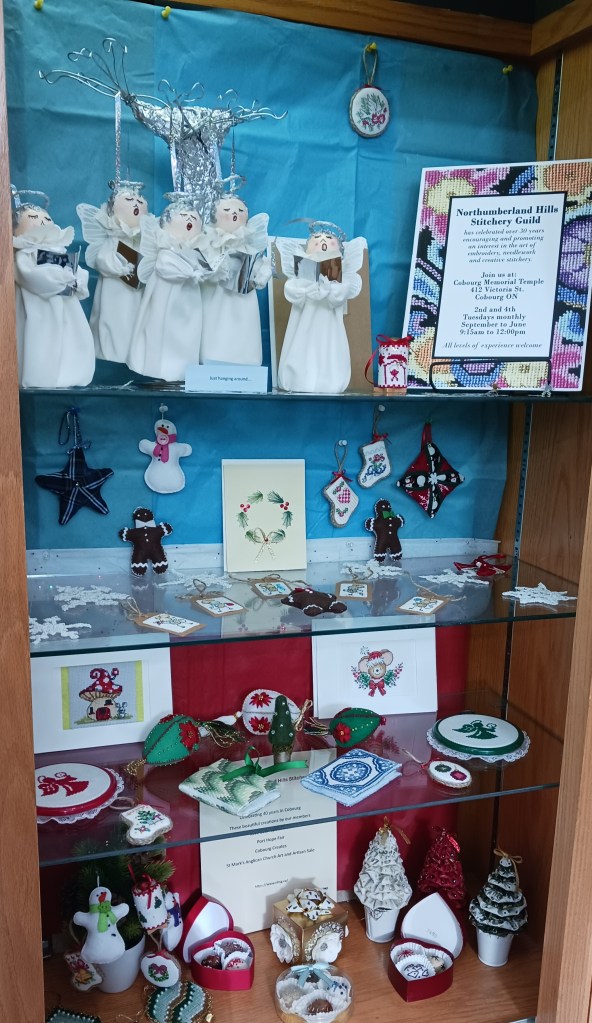 a display of Christmas needlework, in a glass case