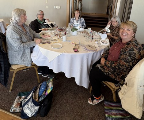5 women stitching around a table