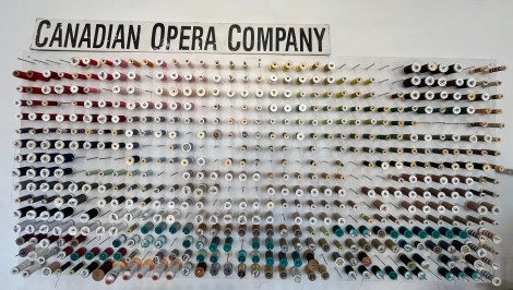 hundreds of thread spools on a wall-mounted spool holder