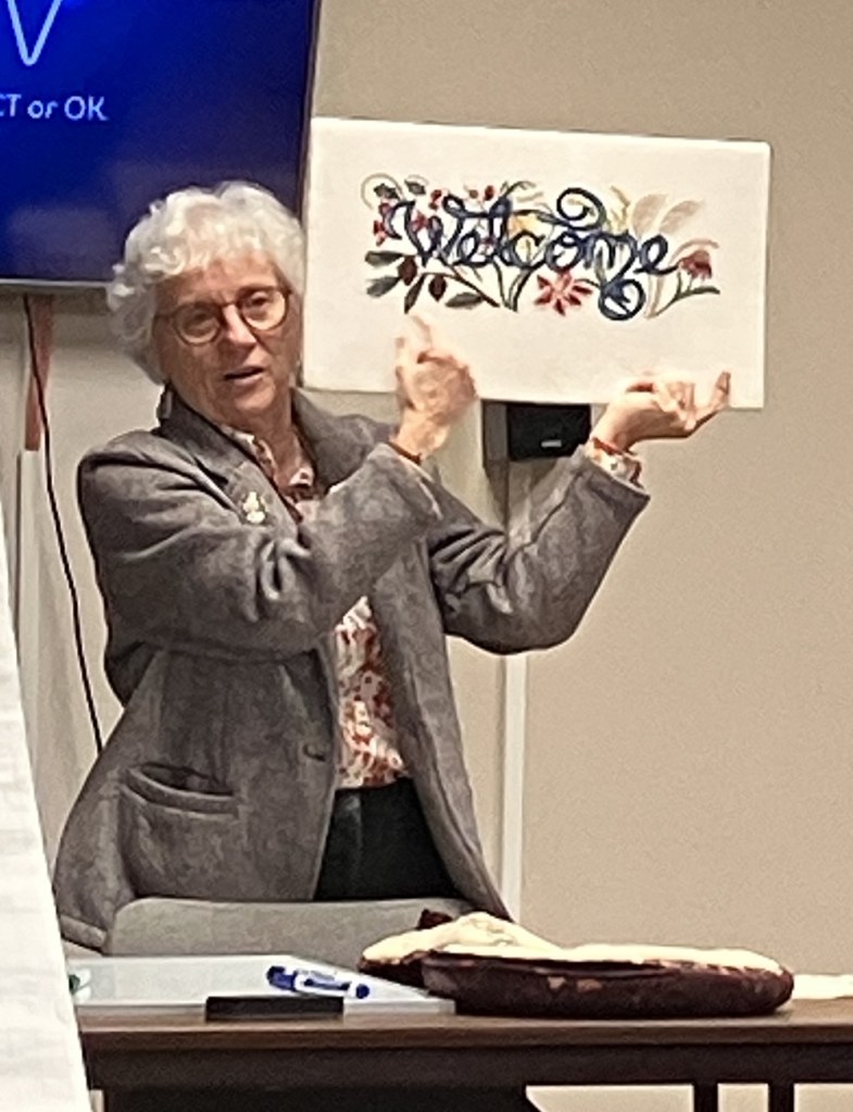 Pat Armour holds a stitched "Welcome" sign