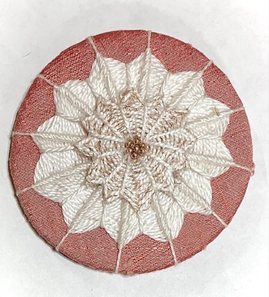 brown medallion covered in white needlelace