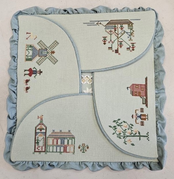 a large folding case with flaps embroidered with classic cross-stitch motifs