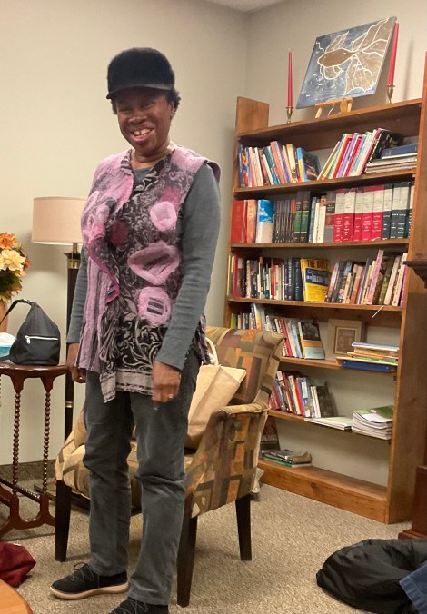 a laughing woman wearing an embroidered vest in pinks and purples