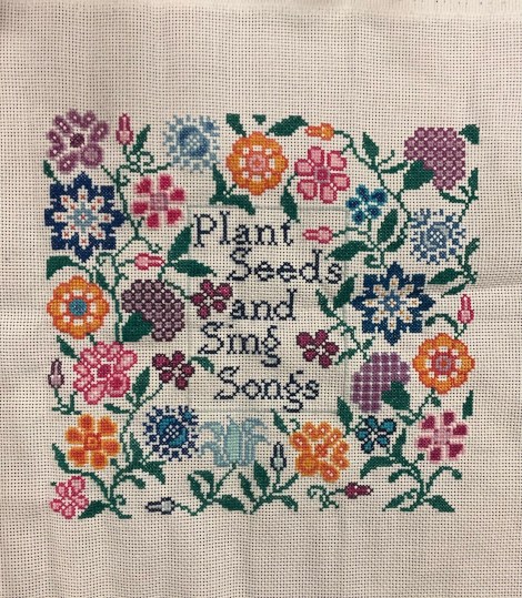 floral cross-stitch with words: Plant Seeds and Sing Songs
