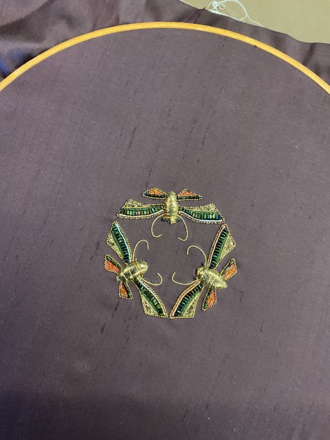 embroidery of three stylized moths forming a circle