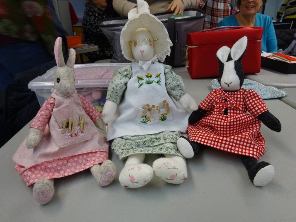 3 stuffed rabbits in dresses and aprons