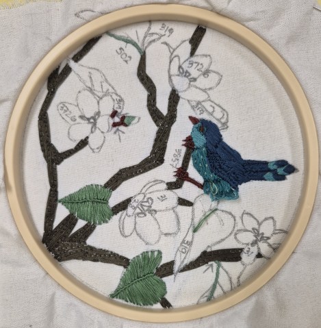 surface embroidery of a blue bird on a flowering branch - work in progress