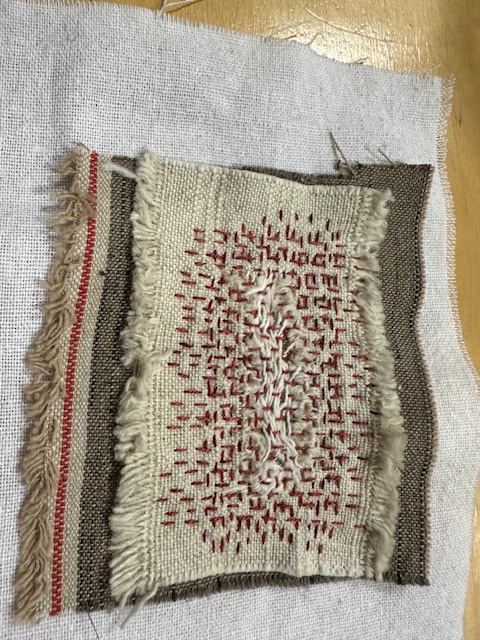 a piece of beige linen stitched to green linen using red thread, in Boro style