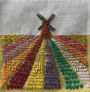 embroidery of a windmill with rows of tulips around it - simple style