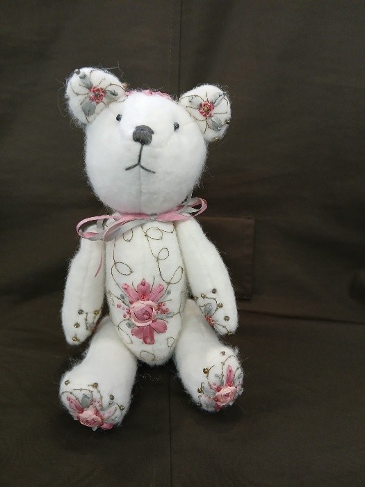 white teddy bear embellished with ribbon roses in pink