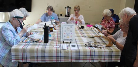 stitchers gathered around a large table with their equipment